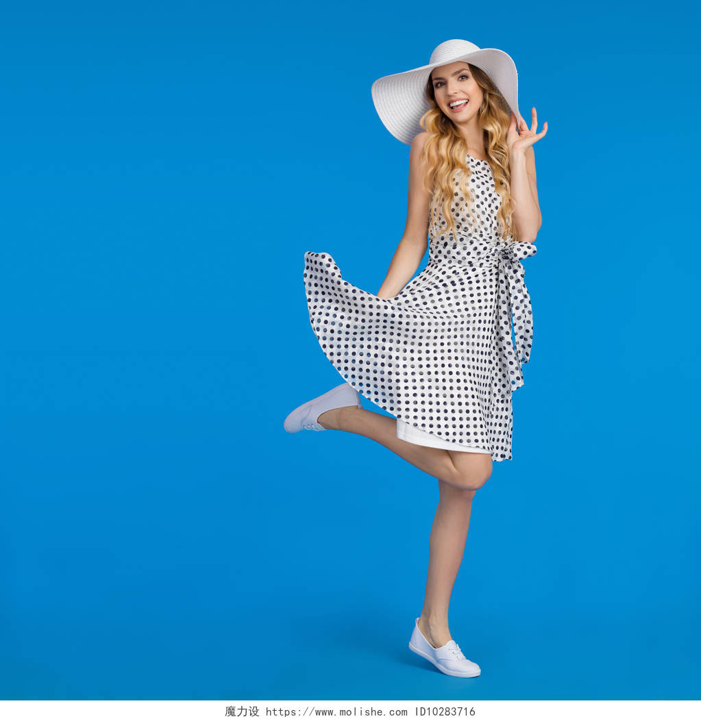 夏天的衣服和运动鞋戴着太阳帽子漂亮的年轻女人正站在一条腿微笑着
